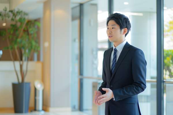 オフィスでプレゼンテーションをするスーツ姿の若い男性ビジネスマン